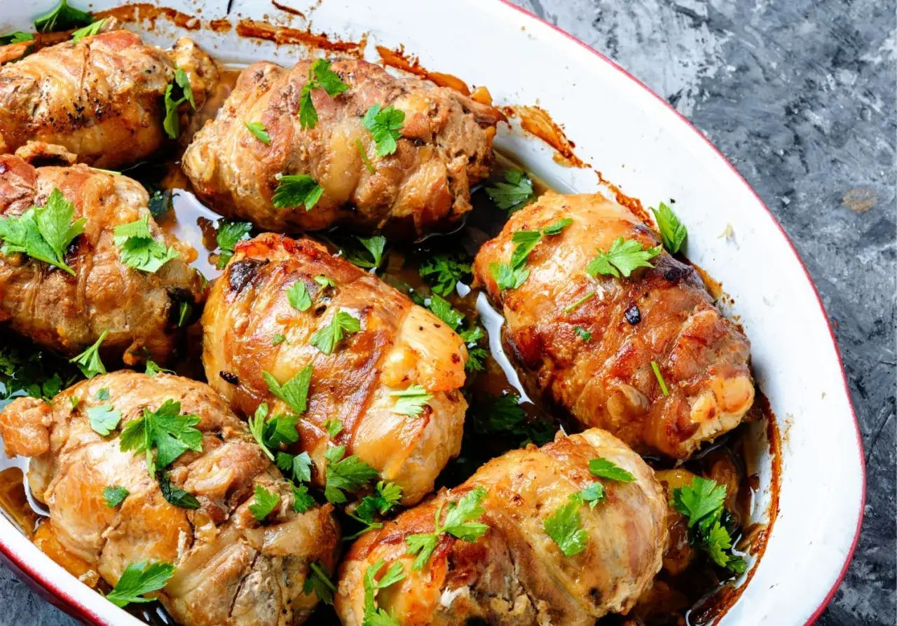 Involtini di carne dorati e succulenti, guarniti con prezzemolo fresco, cotti in una teglia bianca.