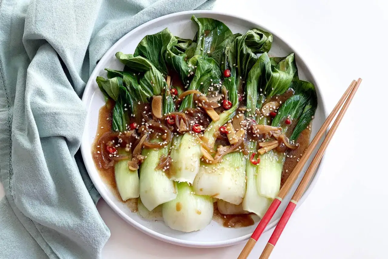 Delizioso pak choi saltato in padella con salsa saporita, peperoncino e semi di sesamo. Un'idea per ricette in padella veloci e gustose.