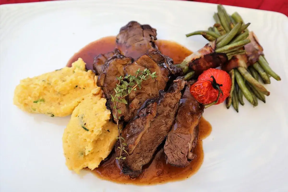 Stracotto di manzo tenerissimo su polenta cremosa, contornato da fagiolini avvolti nel bacon e pomodorino confit.
