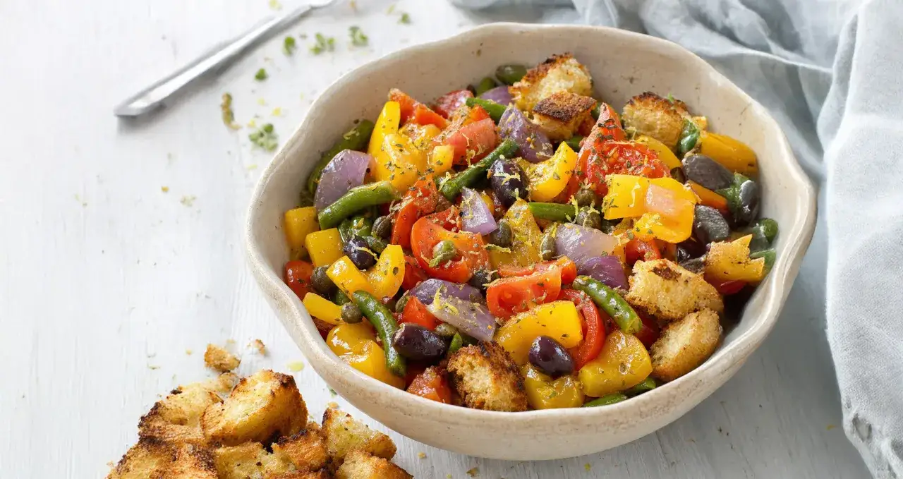 Peperonata ricetta della nonna: un tripudio di colori con peperoni, pomodori, cipolle, olive e crostini.