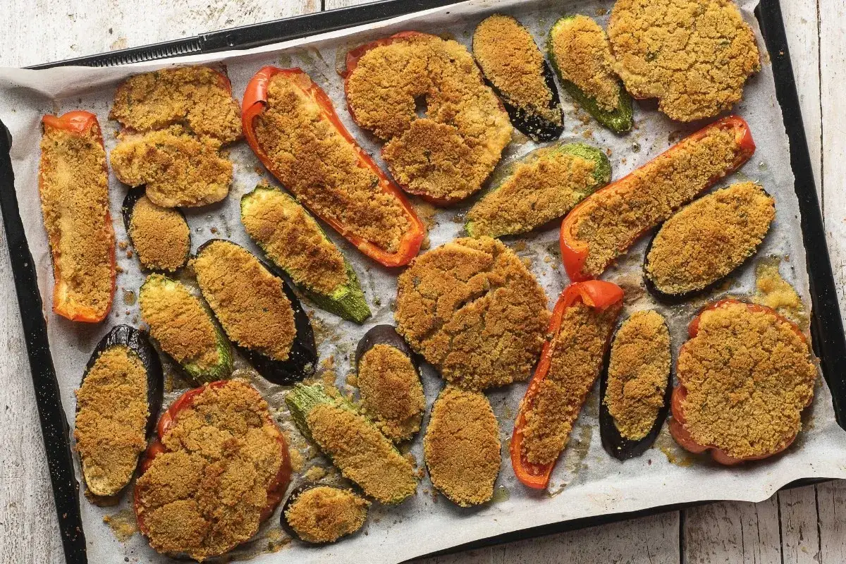 Verdure gratinate al forno: melanzane, zucchine e peperoni ripieni di pangrattato e cotti fino a doratura.