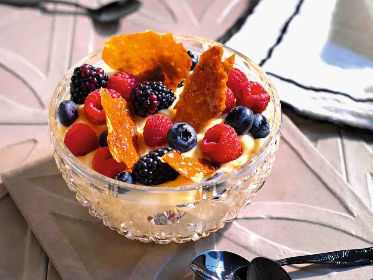 Deliziosa crema pasticcera senza latte, guarnita con frutti di bosco freschi e croccanti cialde caramellate.