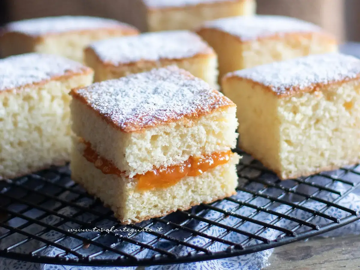 Dolci soffici con yogurt greco e marmellata, spolverati di zucchero a velo, su una griglia.