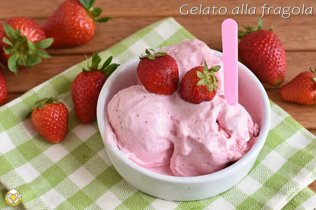 Coppa di cremoso gelato alla fragola, guarnita con fragole fresche, su un tovagliolo a quadri verdi.
