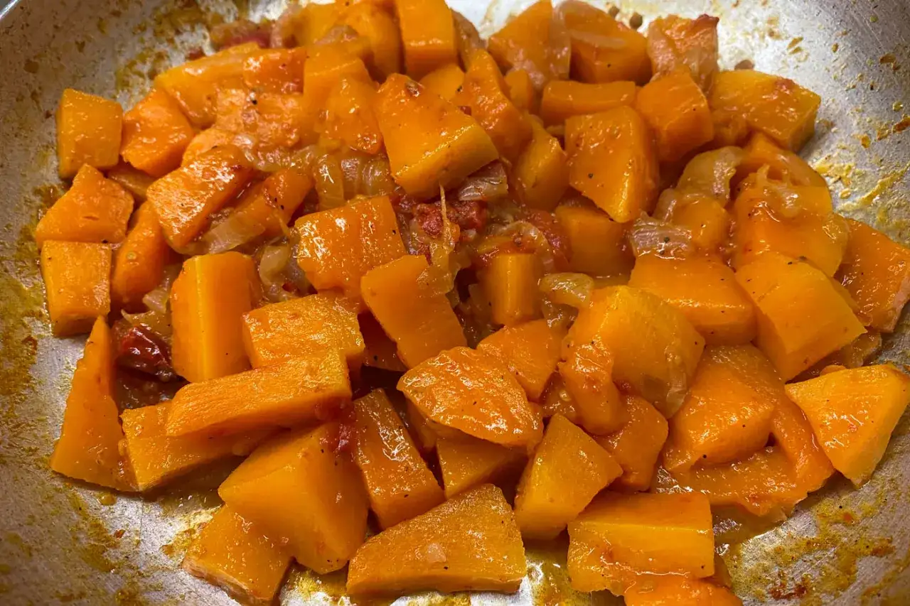Zucca a cubetti cotta in padella con cipolla e pomodoro, un contorno saporito e colorato.