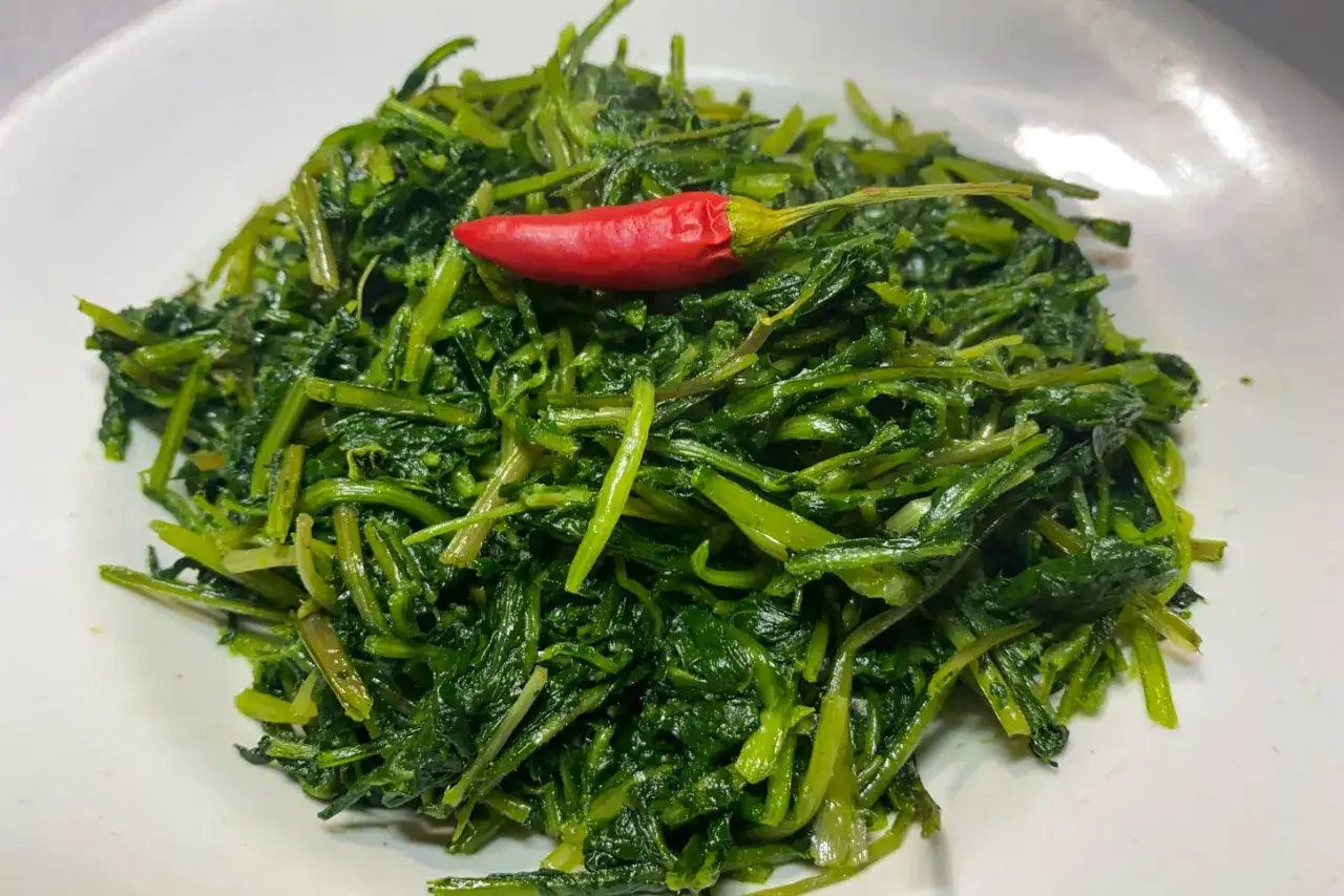 Un gustoso piatto di cicoria in padella, condita con un peperoncino rosso piccante, pronta per essere gustata.
