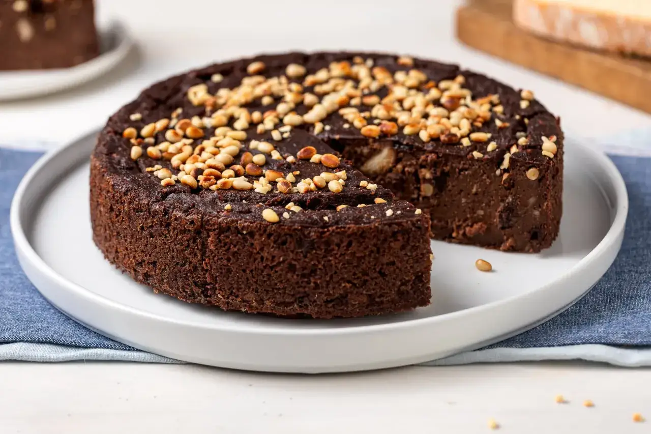 Torta di pane al cioccolato, soffice e ricca, guarnita con pinoli tostati. Un dolce goloso e rustico.