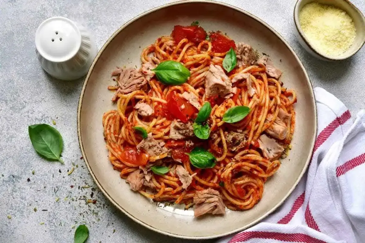Spaghetti al tonno, la ricetta della nonna: un piatto gustoso con tonno, pomodoro e basilico fresco.