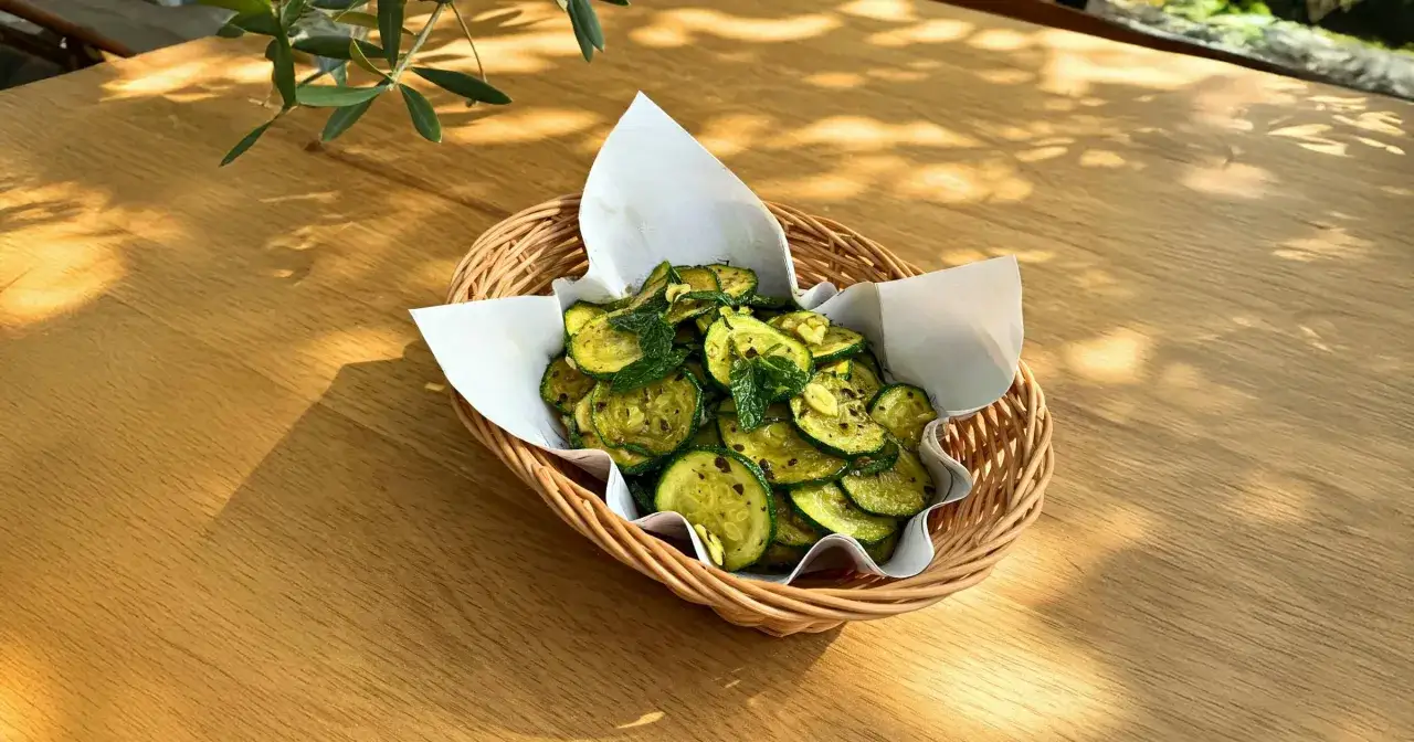 Fette di zucchine saltate con aglio e menta, servite in un cestino di vimini, un delizioso piatto di zucchine alla scapece.
