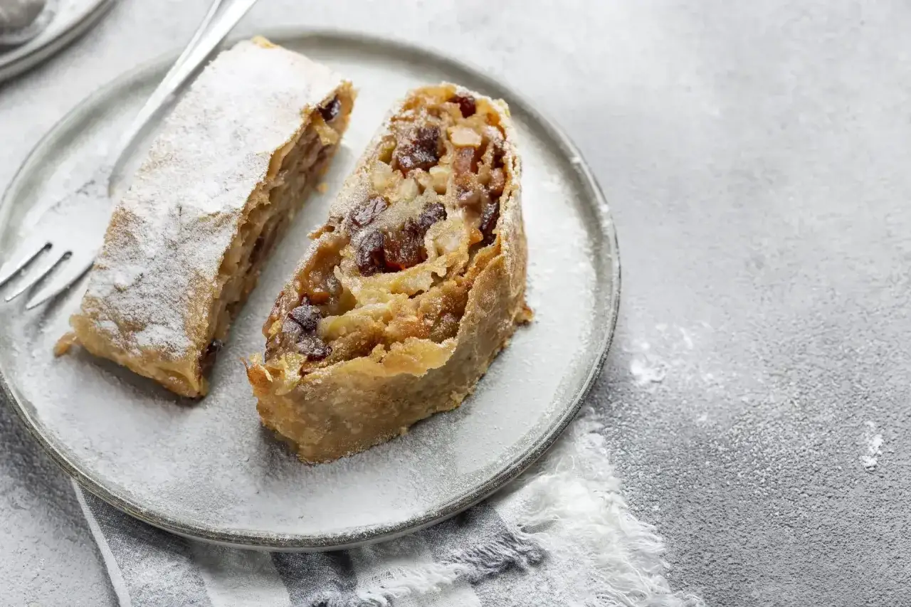 Due fette di strudel di mele su un piatto, spolverate di zucchero a velo. La ricetta strudel di mele &egrave; un classico intramontabile.
