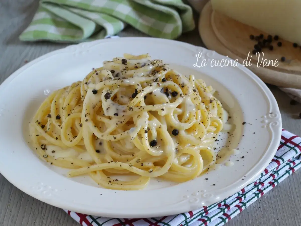Un piatto di spaghetti cremosi al cacio e pepe, conditi con abbondante pepe nero macinato.