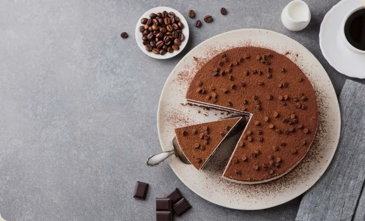 Una deliziosa torta al caff&egrave;, cosparsa di cacao e gocce di cioccolato, pronta per essere gustata con chicchi di caff&egrave; e cioccolato fondente.