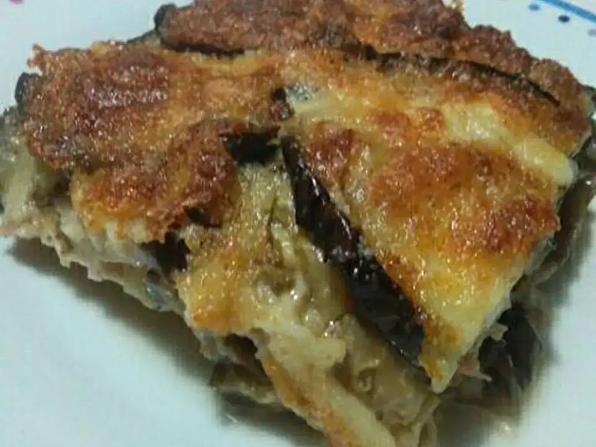 Una fetta di parmigiana di melanzane bianca, dorata e filante, pronta per essere gustata.