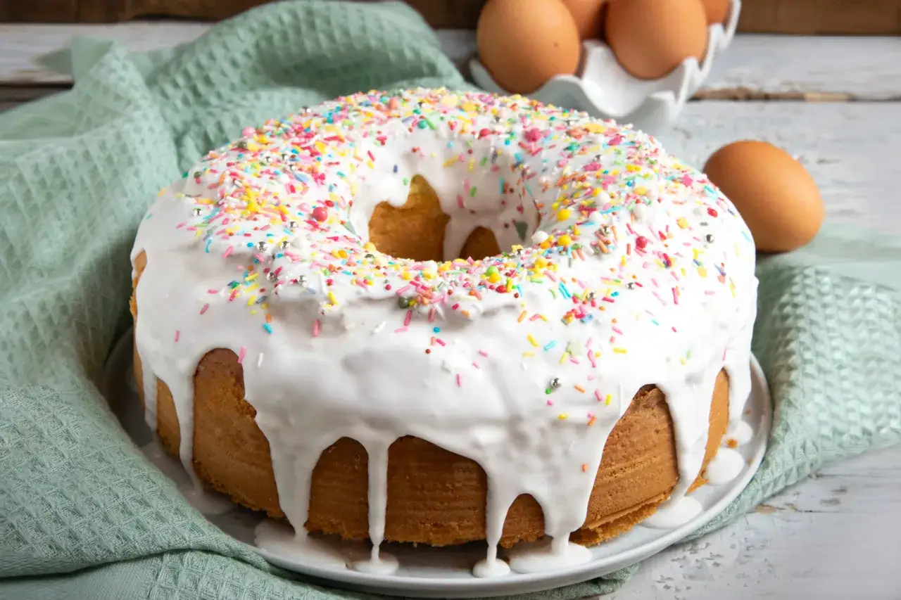 Ciambella con glassa di zucchero bianca e zuccherini colorati, pronta per essere gustata.