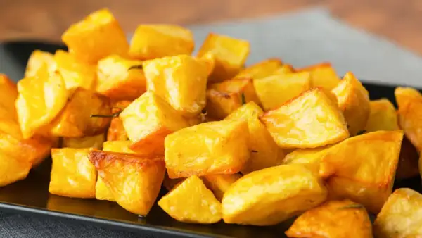 Patate al forno veloci, dorate e croccanti, servite su un piatto nero. Perfette per un contorno rapido e gustoso.