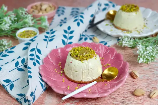 Delizioso semifreddo al pistacchio, guarnito con crema e granella di pistacchi, servito su un piatto rosa.