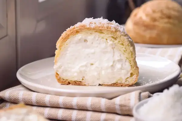 Bignè ripieno di crema, cosparso di zucchero a velo che ricorda soffici fiocchi di neve.