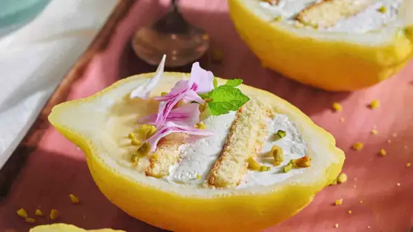 Delizia al limone: un dolce fresco e invitante, servito in un limone scavato, con crema, pan di spagna e pistacchi.