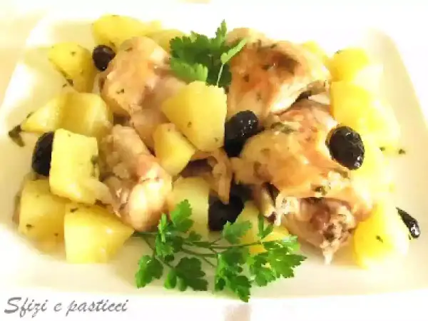 Coniglio in padella con patate e olive nere, guarnito con prezzemolo fresco. Un piatto saporito e invitante.
