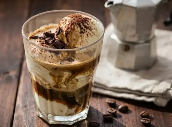 Un delizioso affogato al caffè, con gelato alla vaniglia, cacao e scaglie di cioccolato, pronto per essere gustato.