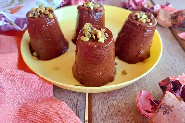 Deliziosi budini cachi e cacao, guarniti con pistacchi tritati, su un piatto giallo.