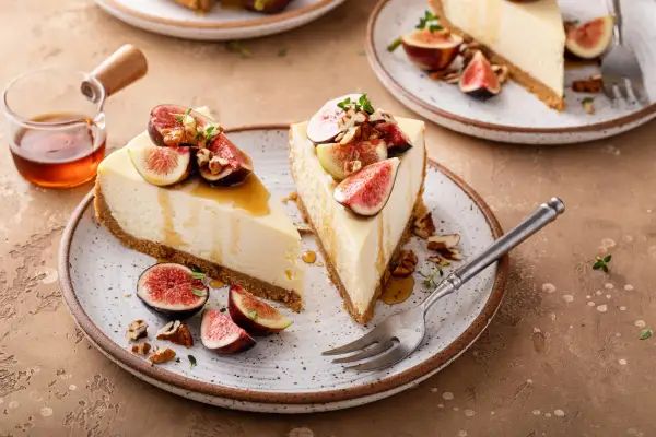 Delizioso cheesecake ai fichi, guarnito con fichi freschi, noci e miele dorato.