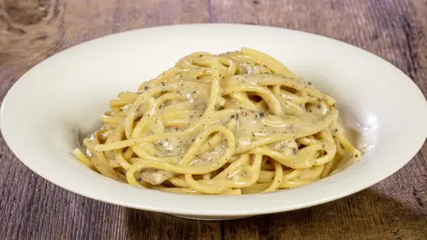 Un piatto di spaghetti cremosi al cacio e pepe, conditi con pepe nero macinato fresco.