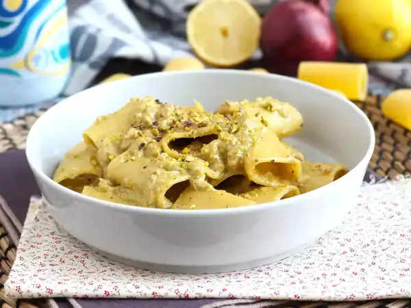 Un piatto di pasta in bianco condita con una crema di pistacchio e guarnita con granella dello stesso frutto secco.