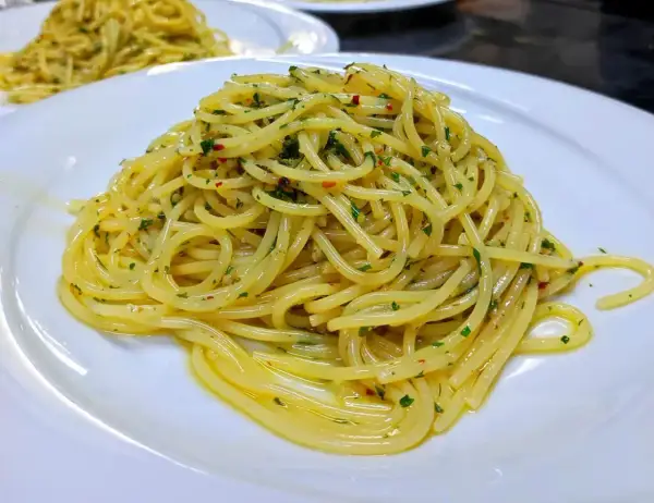 Spaghetti conditi con aglio, olio e peperoncino, guarniti con prezzemolo fresco. Un classico piatto italiano pronto da gustare.