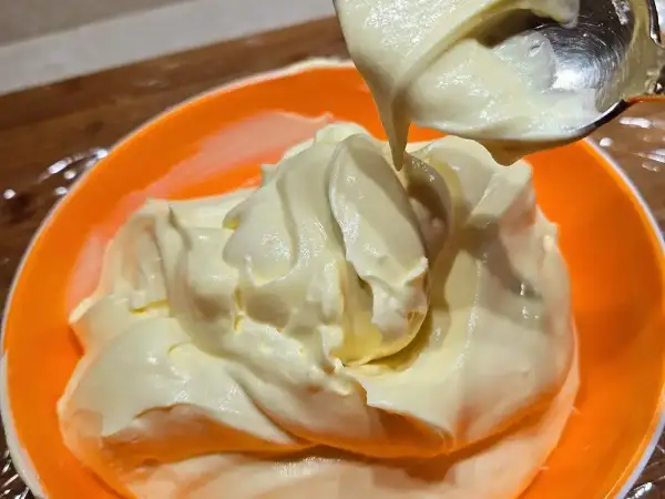 Una ciotola arancione piena di soffice crema al mascarpone, pronta per essere gustata.