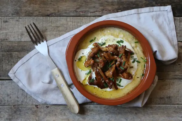 Polenta cremosa con funghi finferli saltati, un piatto rustico e saporito.