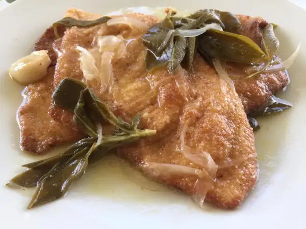 Bistecche in carpione dorate e succulente, condite con cipolle, salvia e aglio in una salsa profumata.