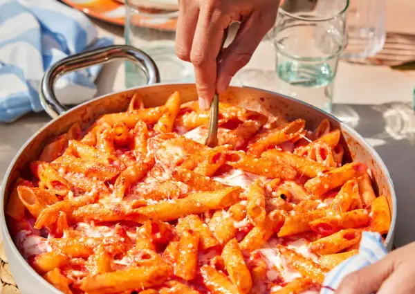 Un primo piatto invitante: pasta alla sorrentina fumante, con pomodoro e mozzarella filante, pronta per essere servita.