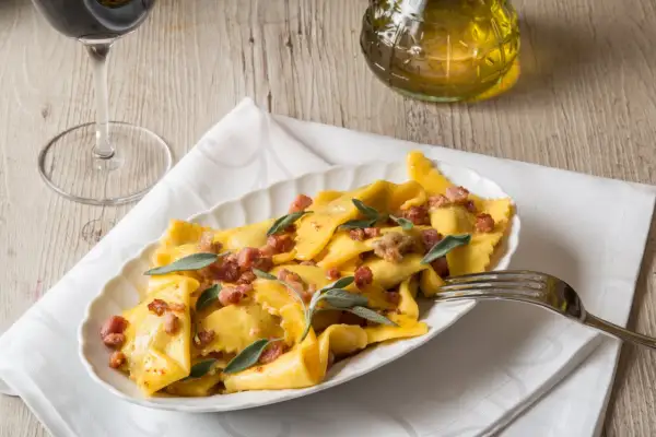 Piatto di casoncelli alla bergamasca conditi con burro, salvia e pancetta croccante.