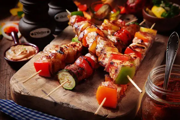 Spiedini di carne succulenti con peperoni, zucchine e pomodori, pronti per essere gustati.