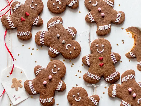 Biscotti di pan di zenzero decorati con glassa bianca e cuoricini rossi, pronti per essere gustati.
