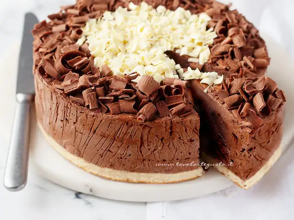 Delizioso semifreddo al cioccolato, ricoperto di riccioli di cioccolato fondente e bianco. Una fetta è stata tagliata, rivelando la sua consistenza cremosa.