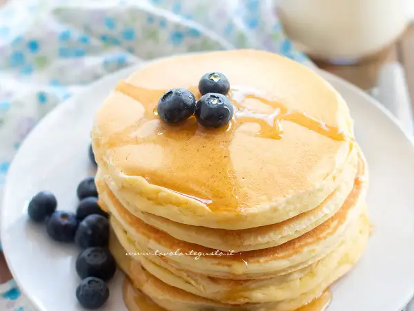 Pancakes soffici con albumi, guarniti con mirtilli freschi e sciroppo d'acero.